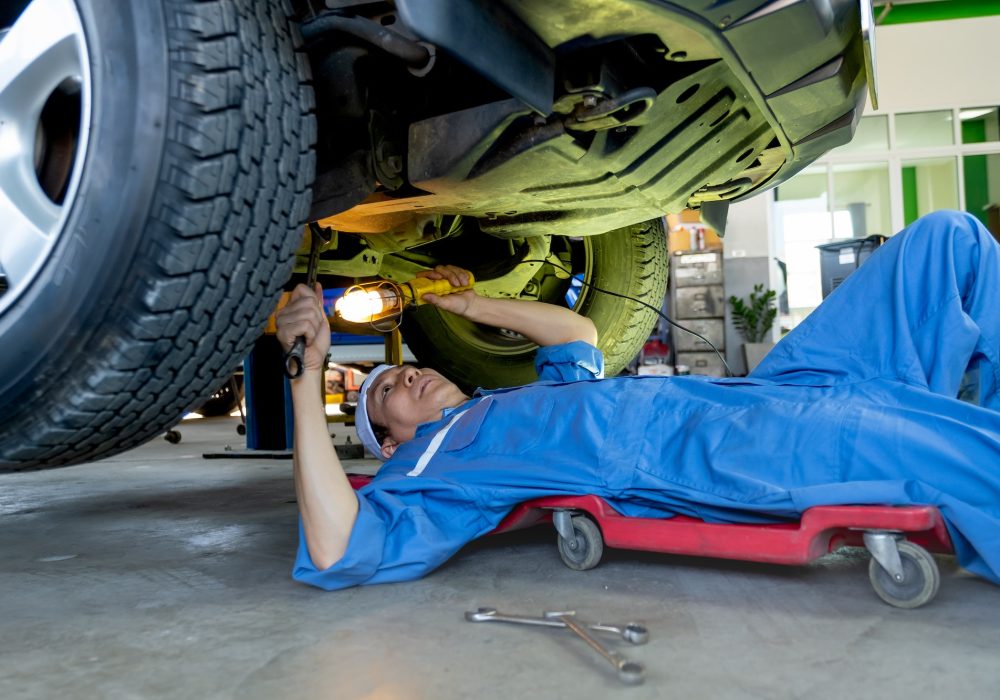 technician-or-garage-worker-lie-down-under-the-car-and-use-lantern-to-guide-for-fix-the-problem.jpg